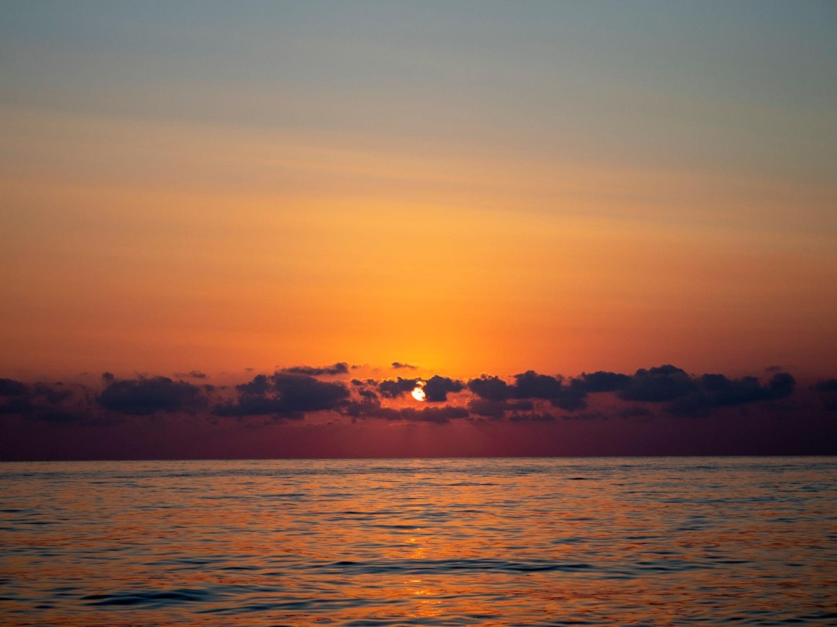 Atardecer sobre el mar con cielo anaranjado y horizonte tranquilo, transmitiendo calma y un ambiente de relajación y meditación.